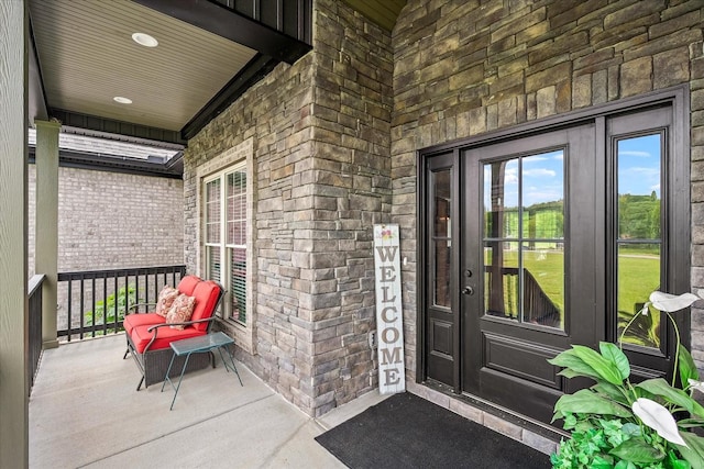entrance to property with stone siding, covered porch, and brick siding