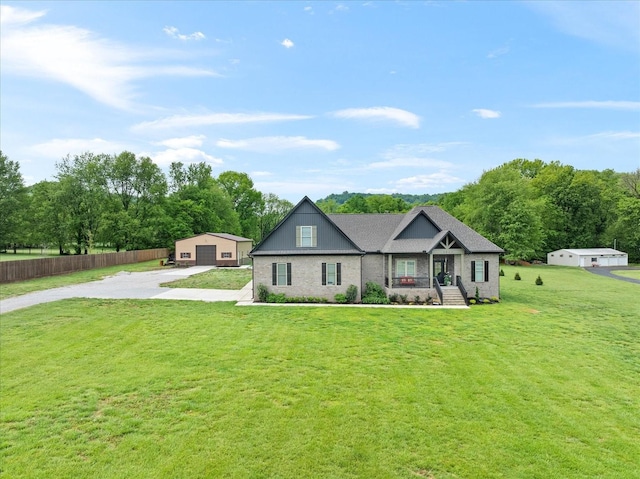 view of front facade with a detached garage, concrete driveway, fence, brick siding, and a front yard