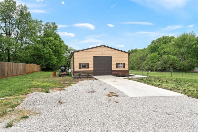 exterior space with an outdoor structure, concrete driveway, and fence