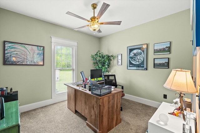 office space featuring light carpet, baseboards, and ceiling fan