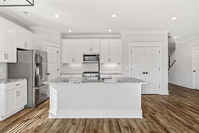 kitchen with dark wood-style floors, crown molding, a kitchen island with sink, appliances with stainless steel finishes, and white cabinetry