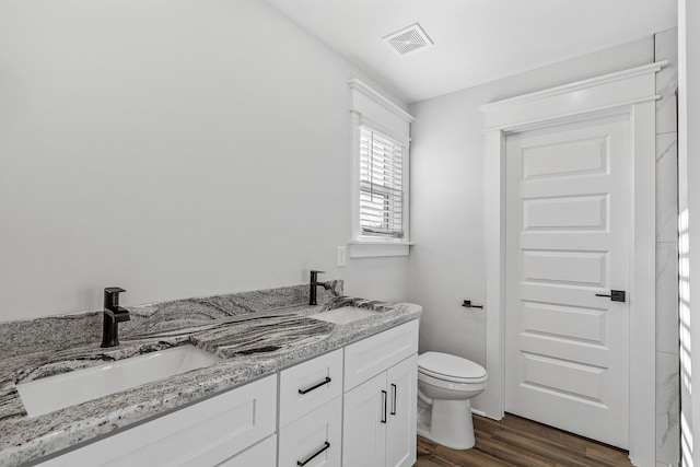 full bathroom with wood finished floors, visible vents, toilet, and a sink