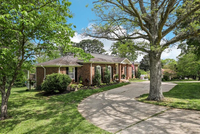 single story home with concrete driveway, a front lawn, and brick siding