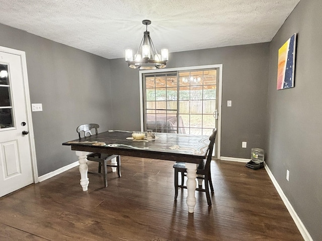 dining room with wood finished floors, a textured ceiling, baseboards, and an inviting chandelier