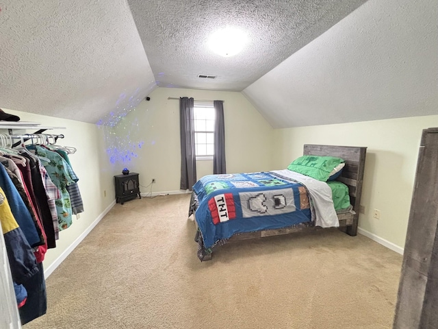 bedroom with lofted ceiling, visible vents, carpet floors, baseboards, and a textured ceiling