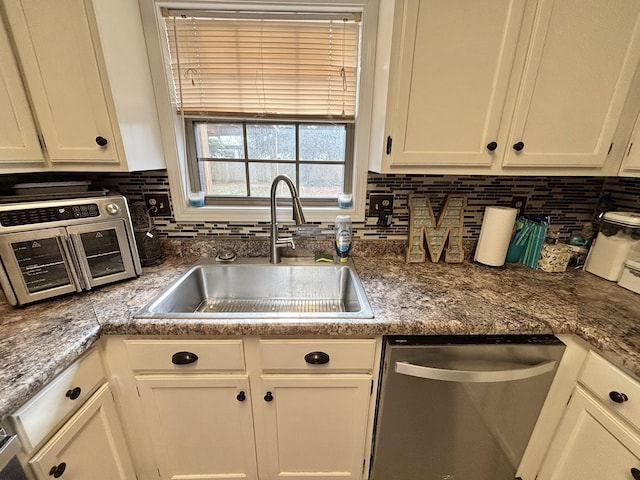 kitchen featuring white cabinets, dishwasher, decorative backsplash, and a sink