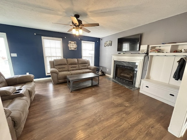 living room with a ceiling fan, a textured ceiling, dark wood-type flooring, and a premium fireplace