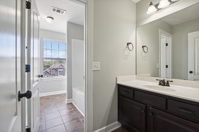 bathroom with a bathing tub, vanity, baseboards, tile patterned flooring, and visible vents