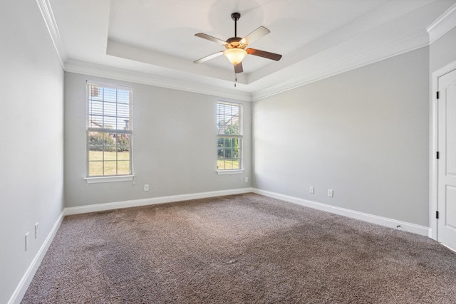 unfurnished room with a tray ceiling, carpet floors, crown molding, baseboards, and ceiling fan