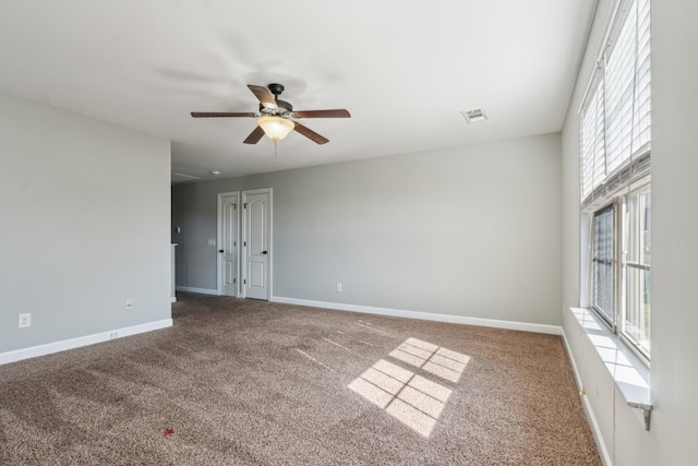 unfurnished room with baseboards, visible vents, carpet floors, and ceiling fan