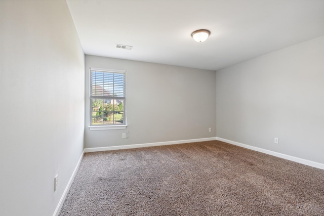 carpeted empty room featuring baseboards and visible vents