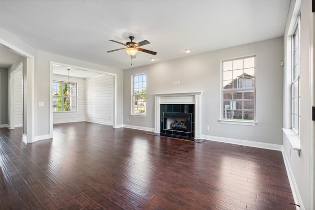 unfurnished living room with ceiling fan, baseboards, a tile fireplace, and plenty of natural light