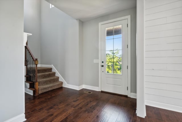 entryway with stairs, baseboards, visible vents, and dark wood-type flooring