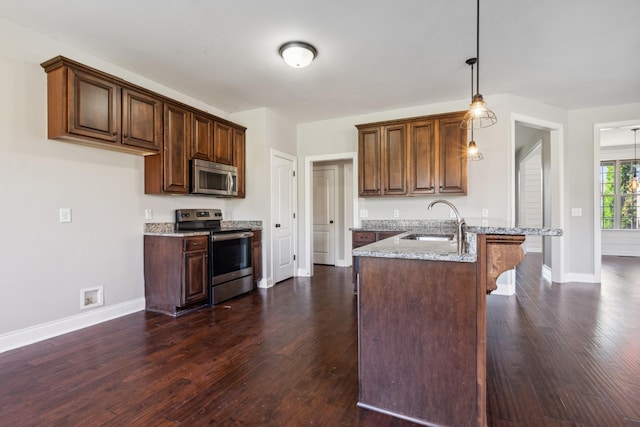 kitchen featuring stainless steel appliances, a sink, dark wood-style flooring, baseboards, and light stone countertops