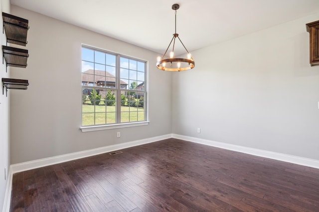 spare room featuring dark wood-style floors, visible vents, baseboards, and an inviting chandelier