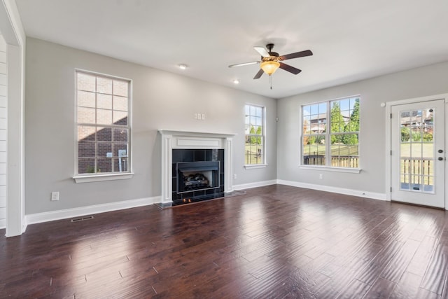 unfurnished living room with baseboards, a ceiling fan, dark wood-style flooring, and a tiled fireplace