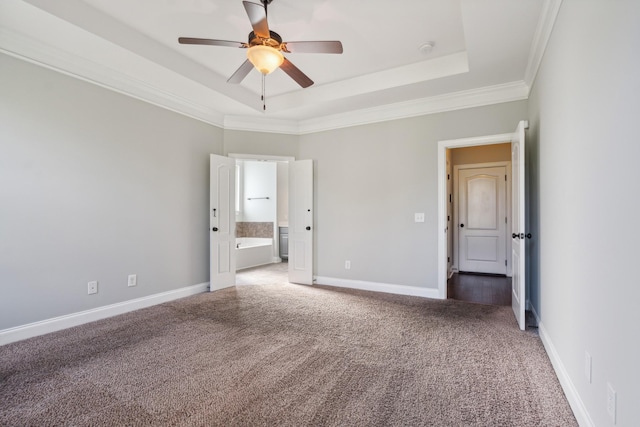 unfurnished bedroom featuring a raised ceiling, ornamental molding, baseboards, carpet flooring, and ensuite bathroom