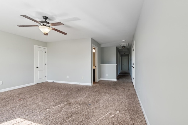 carpeted empty room featuring attic access, baseboards, and a ceiling fan