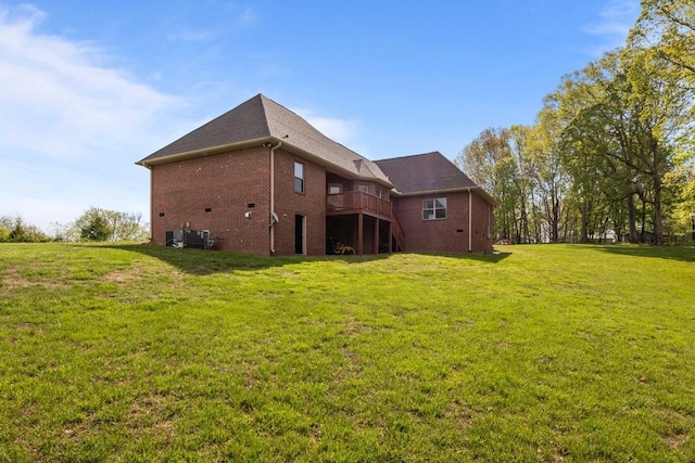 back of house with a wooden deck, brick siding, a yard, and central air condition unit