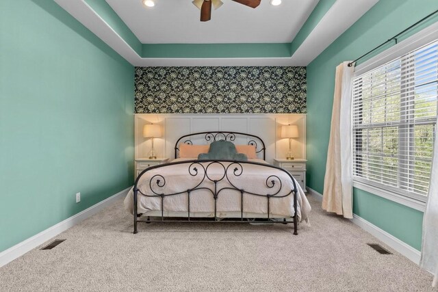 carpeted bedroom with an accent wall, visible vents, and baseboards