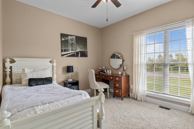 carpeted bedroom with a ceiling fan, multiple windows, and visible vents