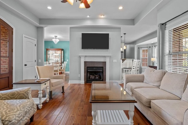 living room with plenty of natural light, a ceiling fan, a tile fireplace, and wood-type flooring
