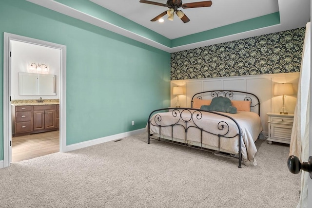 carpeted bedroom featuring wallpapered walls, connected bathroom, ceiling fan, baseboards, and visible vents
