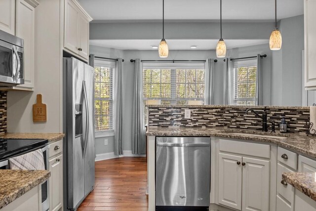 kitchen with stainless steel appliances, a sink, tasteful backsplash, baseboards, and hardwood / wood-style flooring