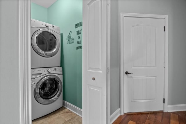 washroom with baseboards and stacked washer and clothes dryer