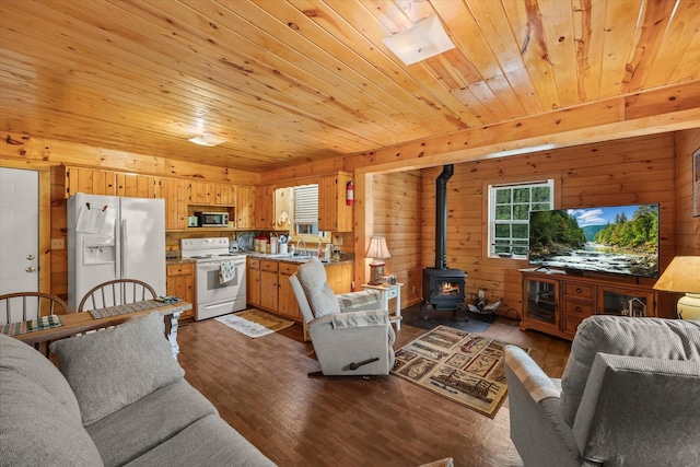 living area featuring wooden walls, a wood stove, wooden ceiling, and dark wood-style floors
