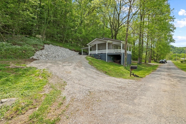 view of front facade with dirt driveway and a forest view
