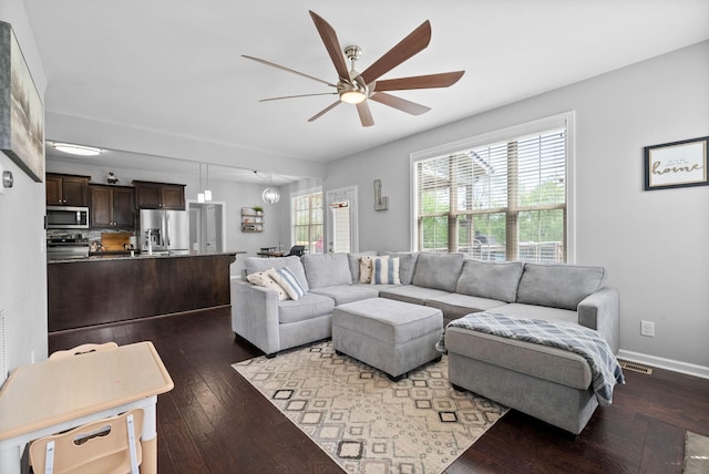 living area featuring baseboards, a ceiling fan, hardwood / wood-style floors, and visible vents