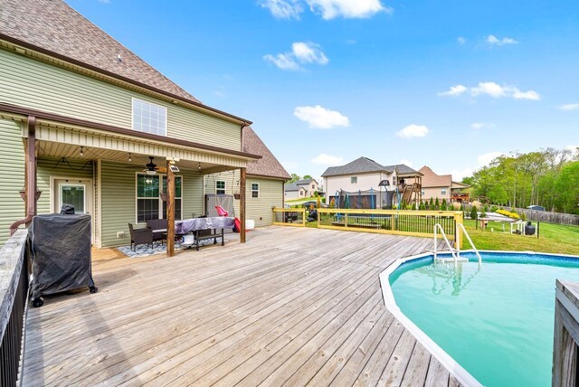 pool with a wooden deck, an outdoor hangout area, a yard, and ceiling fan