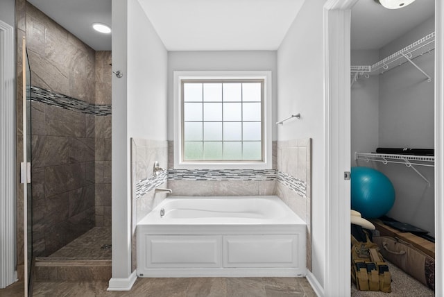bathroom featuring a garden tub, a shower stall, and a walk in closet
