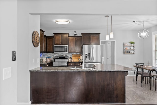 kitchen with stainless steel appliances, a sink, dark brown cabinets, baseboards, and backsplash