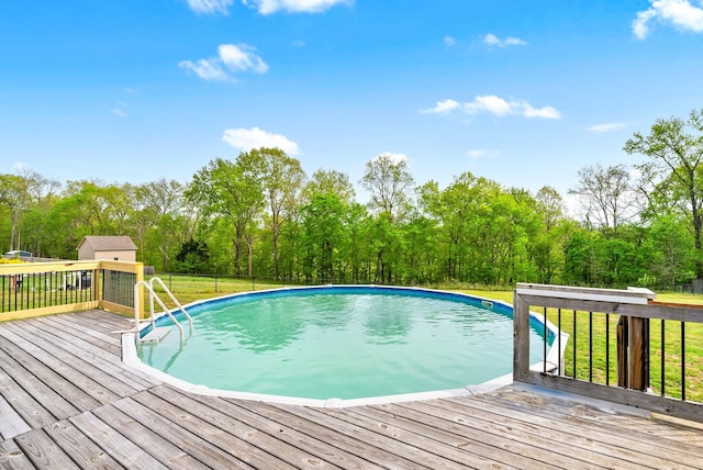 pool featuring a wooden deck, a lawn, an outdoor structure, and a shed