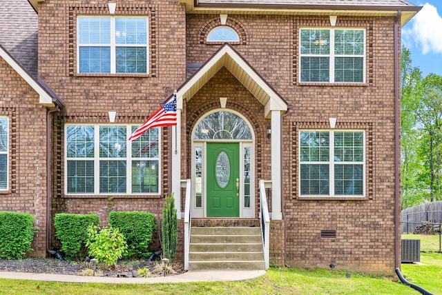 entrance to property featuring central AC unit and brick siding