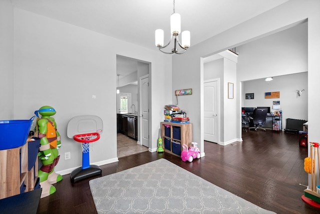 game room with baseboards, wood finished floors, a sink, and a chandelier