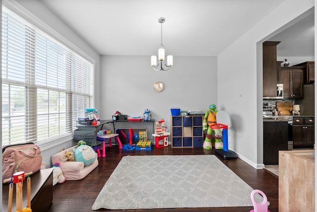 game room with dark wood finished floors, an inviting chandelier, and baseboards