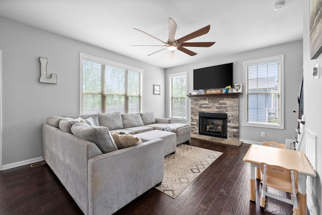 living room featuring a fireplace, dark wood-style flooring, baseboards, and ceiling fan