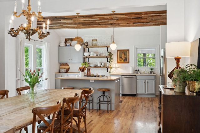 kitchen with an inviting chandelier, stainless steel dishwasher, light wood-type flooring, a center island, and gray cabinetry