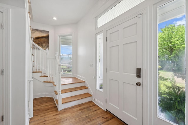 foyer with stairway, a wealth of natural light, and light wood-style floors