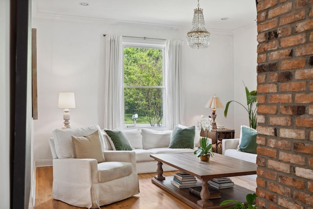 living area with wood finished floors, ornamental molding, baseboards, and a notable chandelier