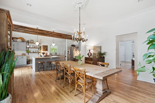 dining space featuring a notable chandelier, baseboards, crown molding, and light wood-style flooring