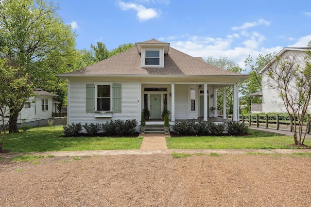 view of front of home featuring fence, a porch, a shingled roof, and a front yard