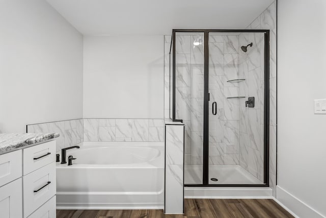 full bath featuring a bath, vanity, wood finished floors, and a stall shower