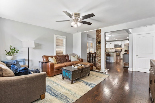 living area featuring dark wood-style floors, ceiling fan, and decorative columns