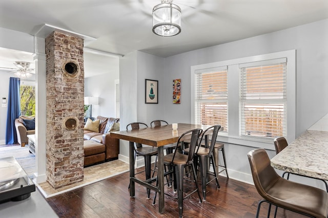 dining space with ceiling fan with notable chandelier, baseboards, and dark wood-style floors