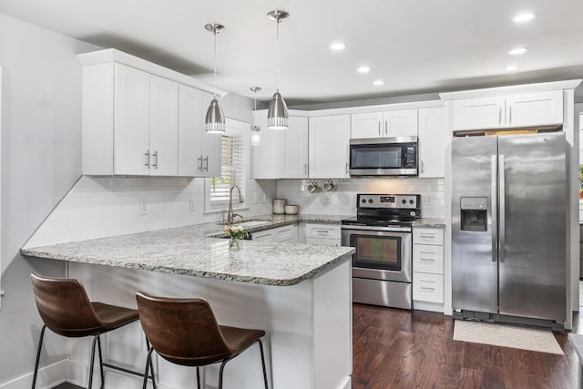 kitchen featuring white cabinets, stainless steel appliances, a peninsula, and a sink