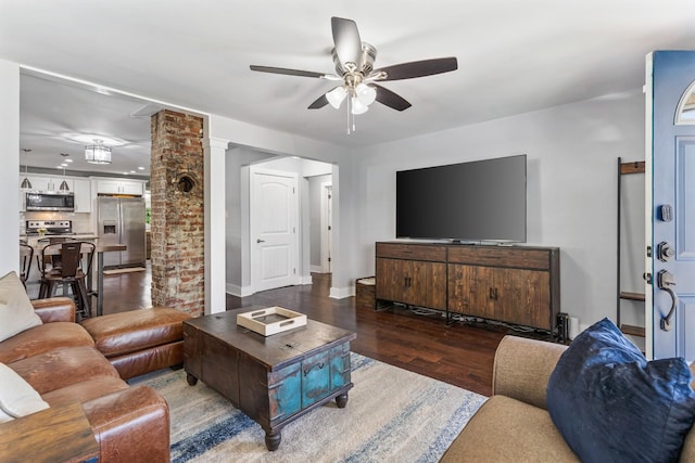 living area with baseboards, decorative columns, wood finished floors, and ceiling fan